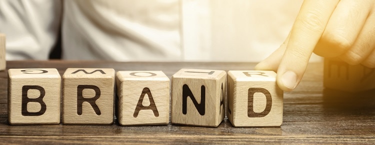 Businessman puts wooden blocks with the word Brand. Business, marketing, and advertising. Name, term, design, symbol that identifies one seller's good or service.